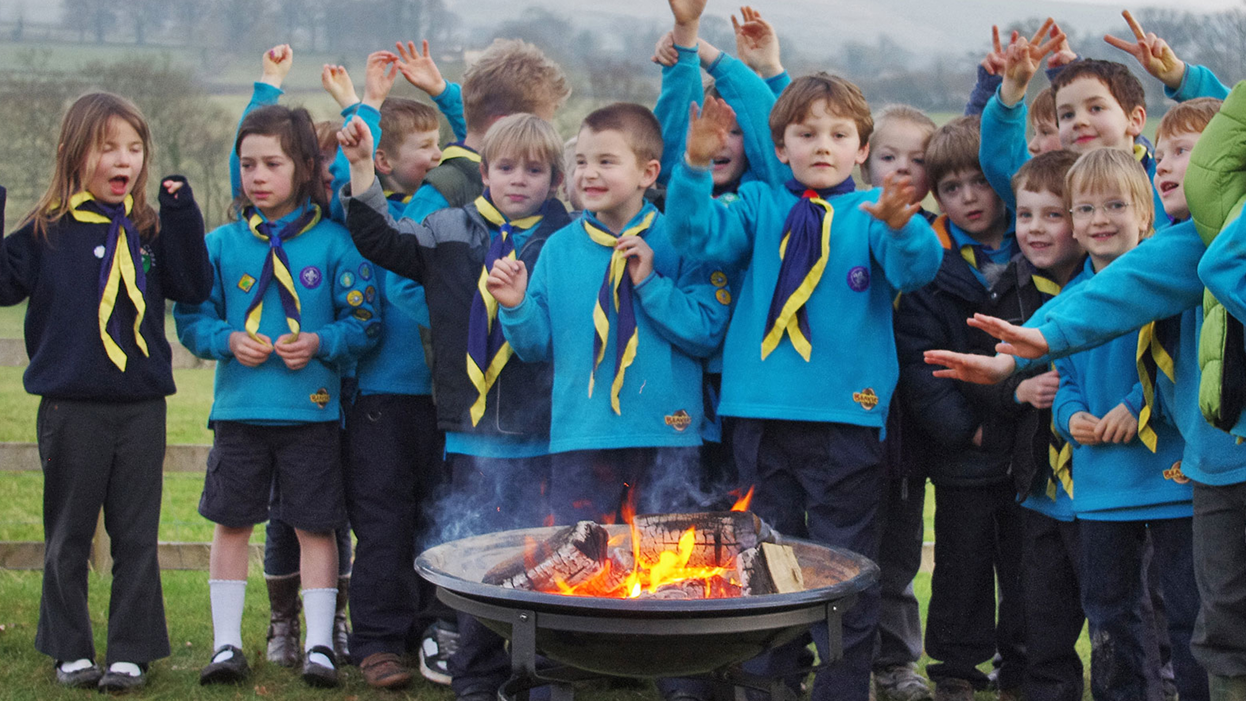 Children dressed in Beavers uniforms tending to a campfire